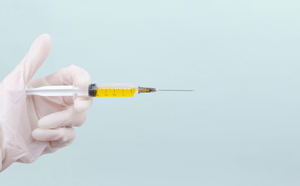 Hand met handschoen houdt een injectienaald vast